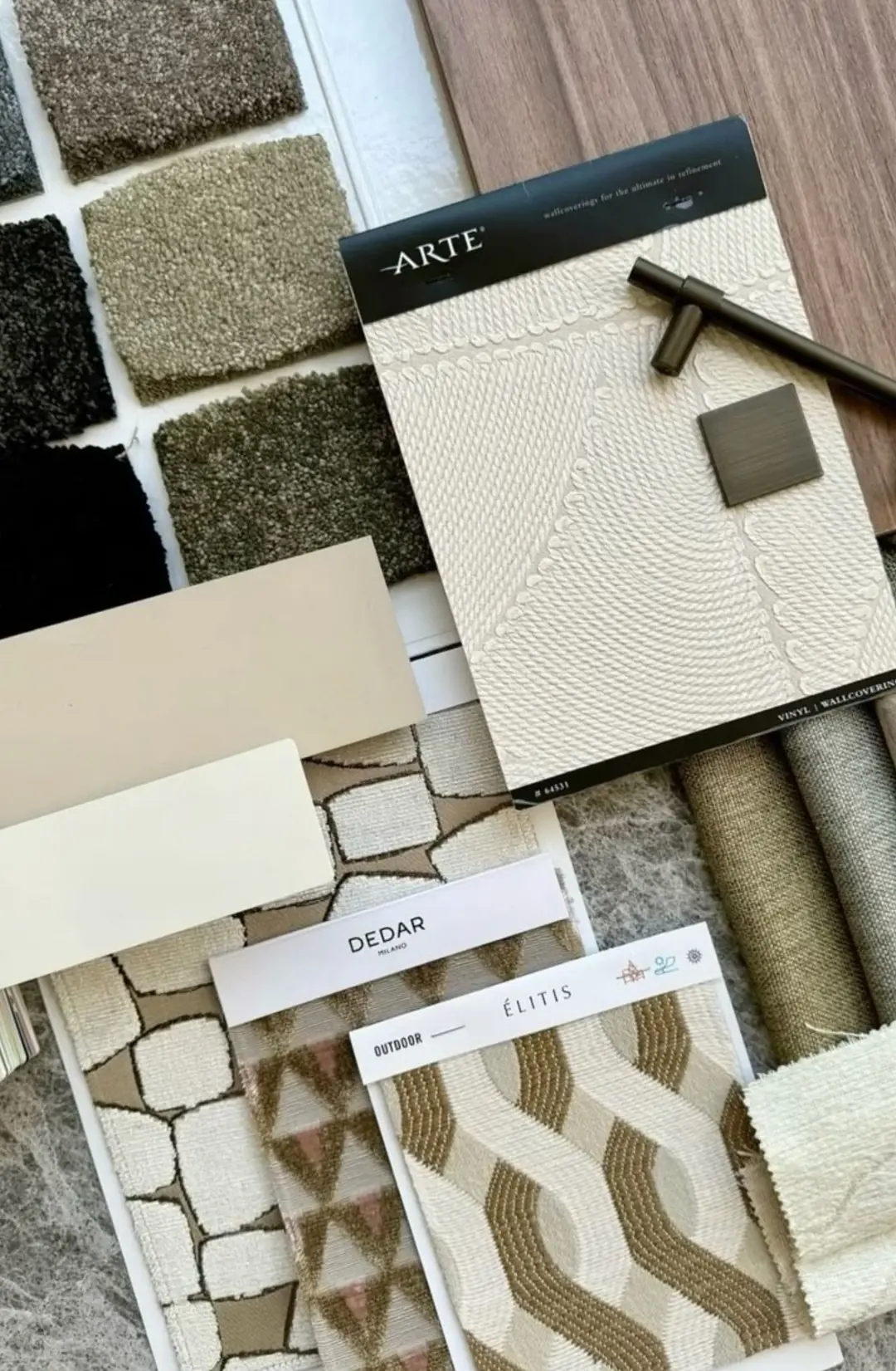 Materiaalstalen van tapijt, meubelstof, behang en hout naast elkaar uitgelegd